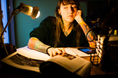 Young woman studying while sitting on table