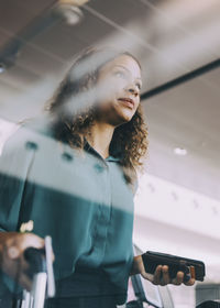 Low angle view of businesswoman holding smart phone while standing at airport