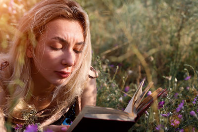 Young woman reads a book in the field in nature. summer evening