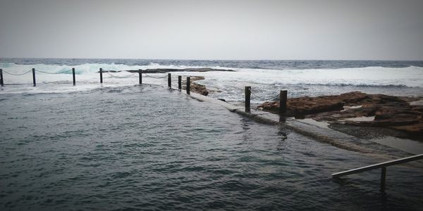 Wooden posts on beach against clear sky