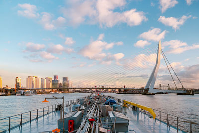 Sailboats on bridge over river against sky during sunset