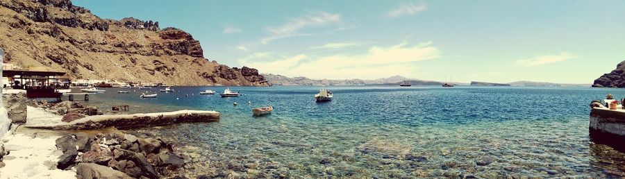 Boats in sea with mountain range in background