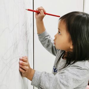 Side view portrait of a girl looking away against wall