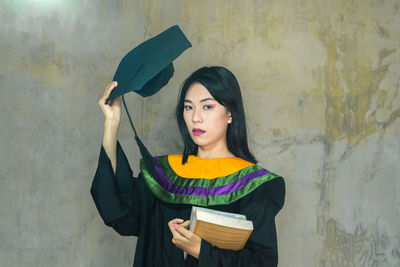 Portrait of beautiful woman standing against wall