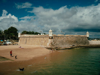 People at beach against cloudy sky