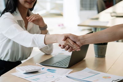 Midsection of woman using laptop on table
