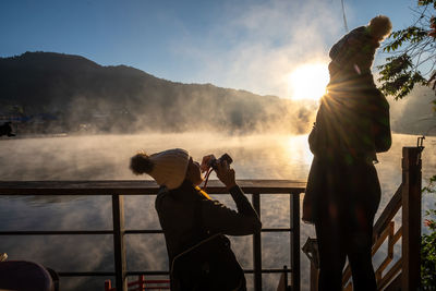 People photographing on mountain against sky