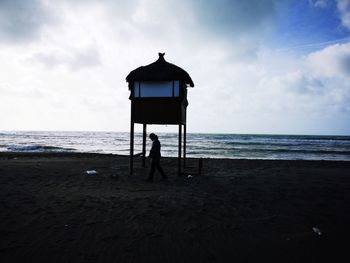 Silhouette people on beach by sea against sky