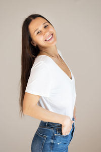 Portrait of young woman standing against wall