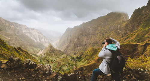 Rear view of man photographing while standing on mountain