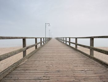 Wooden pier leading towards sea against sky
