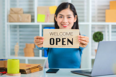 Portrait of woman holding smart phone on table