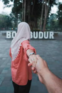 Midsection of couple holding hands