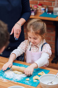 Midsection of woman guiding guide in rolling dough