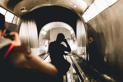 Rear view of people on illuminated underground walkway