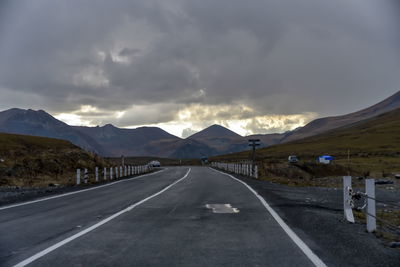 Empty road along mountain range against sky