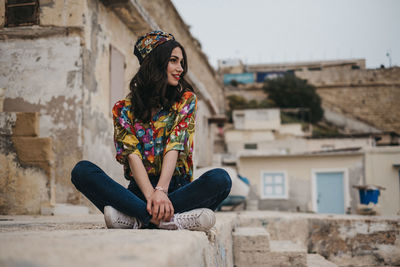 Young woman sitting against building