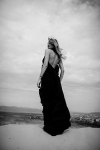Woman standing on beach against sky