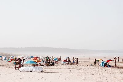 People at sandy beach against sky