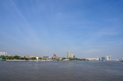 Sea by buildings against blue sky