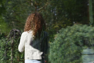 Rear view of woman standing against trees