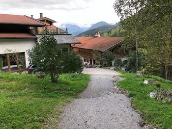 Footpath amidst houses and trees against sky