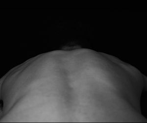 Rear view of shirtless man against black background