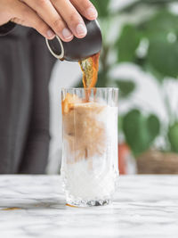 Midsection of person holding ice cream in glass on table