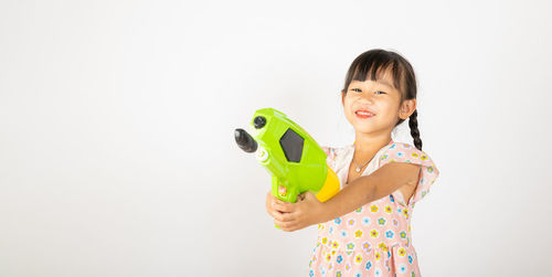Portrait of young woman holding toy against white background