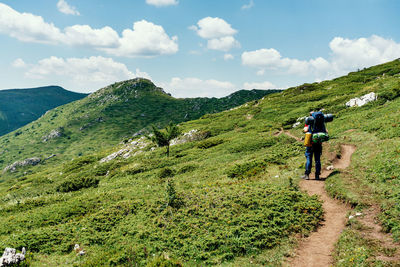 Rear view of man walking on mountain against sky