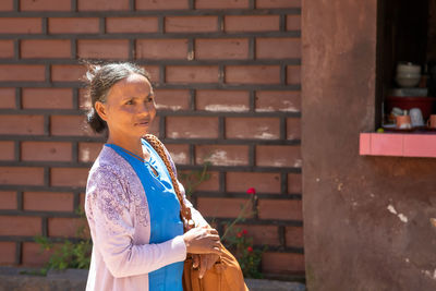 Portrait of smiling woman standing against brick wall