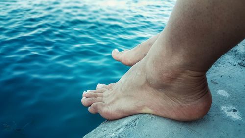 Low section of person sitting on shore