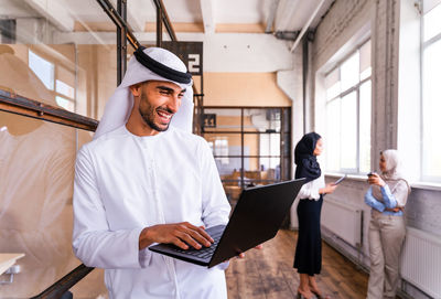 Portrait of young woman using laptop while sitting in office