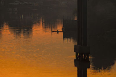 Bird flying over lake at sunset