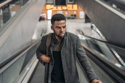 Man looking away while standing on escalator