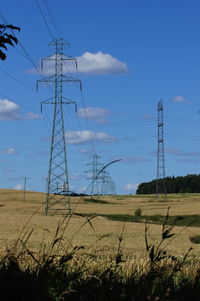 Electricity pylon on field against sky