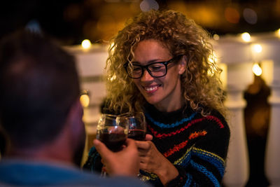 Smiling woman toasting drinks with partner at night