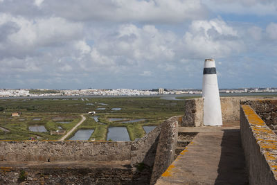 Lighthouse amidst buildings against sky