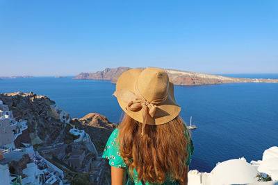 Rear view of woman in sea against clear blue sky