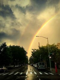 Rainbow over road against sky