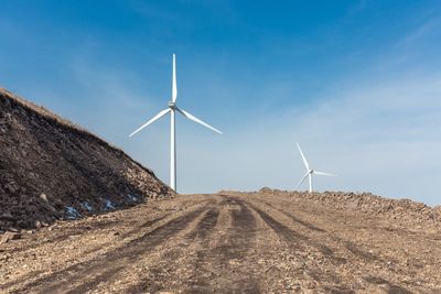 Close-up of windmill on field against blue sky