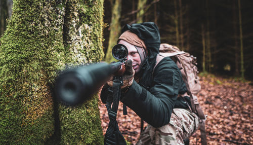 Side view of young man standing in forest