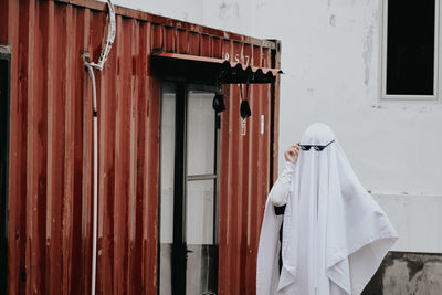 Rear view of woman standing against door of building