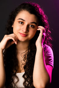 Portrait of young beautiful cheerful woman with one hand in her hair and another on her face. 