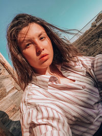 Portrait of young woman standing against sky