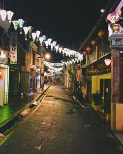 Illuminated decoration hanging amidst buildings in city at night