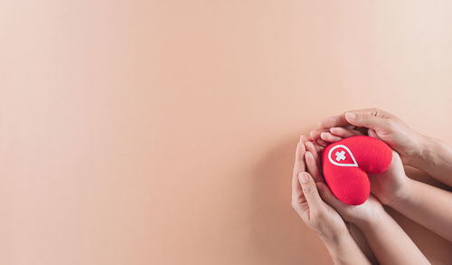 Close-up of woman holding red hand against wall