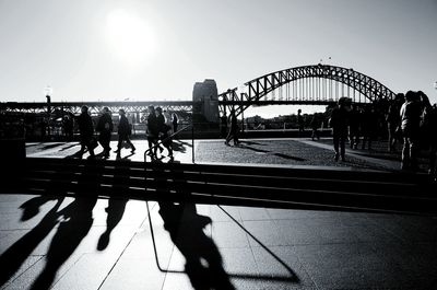 People walking in city by sydney harbor bridge against clear sky