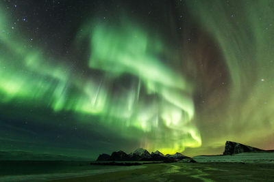 Scenic view of beach against aurora borealis at night