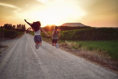 Rear view of woman on field against sky during sunset